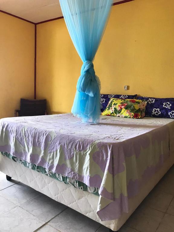 una cama con una cortina azul encima en Fare OKAI, en Fitii