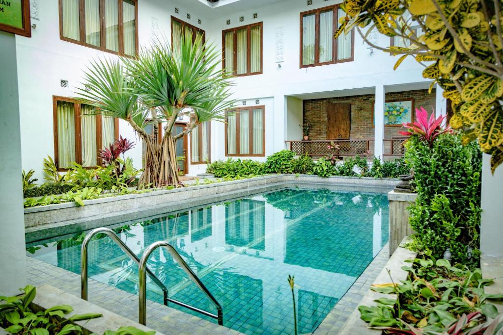 a pool in the middle of a house with plants at Family Hotel Gradia 2 in Batu