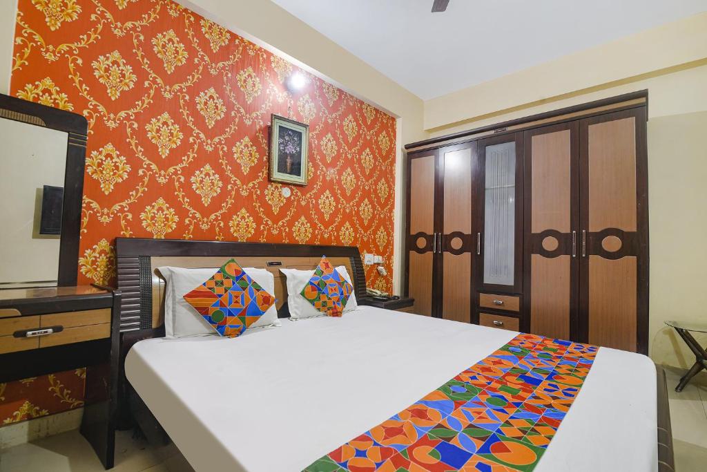 a bedroom with a bed and a orange wall at FabHotel Maadhavam Residence in Patna