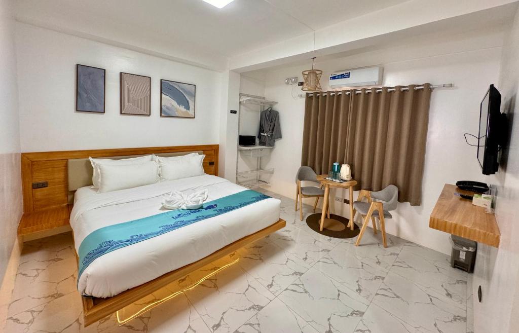 ein Schlafzimmer mit einem Bett und einem Schreibtisch in einem Zimmer in der Unterkunft LuckyTito Dmall Boracay in Boracay