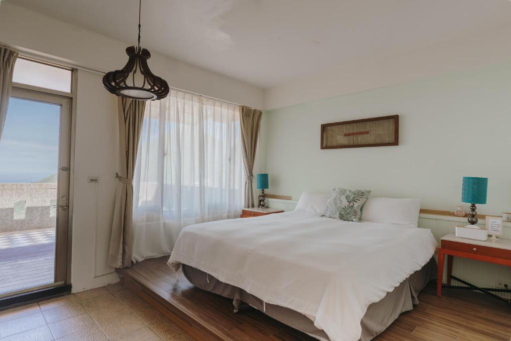 um quarto com uma grande cama branca e uma janela em Mountain Traveler Inn em Jiufen