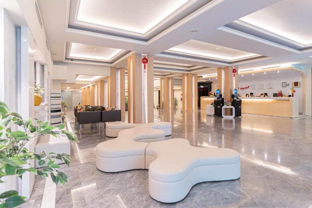 a lobby with white chairs and tables in a building at Guide Hotel Kaohsiung Liuhe in Kaohsiung