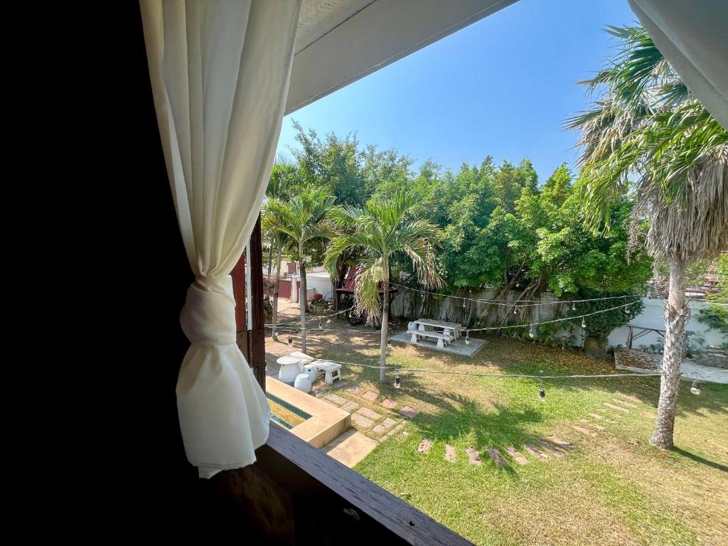 uma janela com vista para um quintal com palmeiras em พลารมย์ รีสอร์ต แอนด์ โฮมสเตย์ em Ban Chang