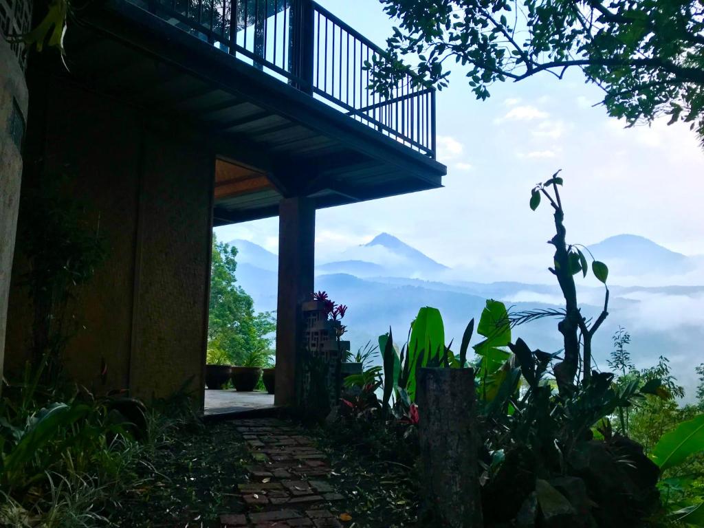 une maison avec un balcon et des montagnes en arrière-plan dans l'établissement Kraras Munduk Guest House & DonBiyu Rendezvous Restaurant, à Munduk