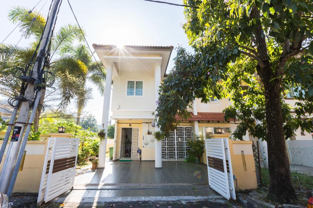 una casa blanca con puertas blancas y un árbol en Cosy HomeStay at Penang Island -Beach and Village, en Bayan Lepas