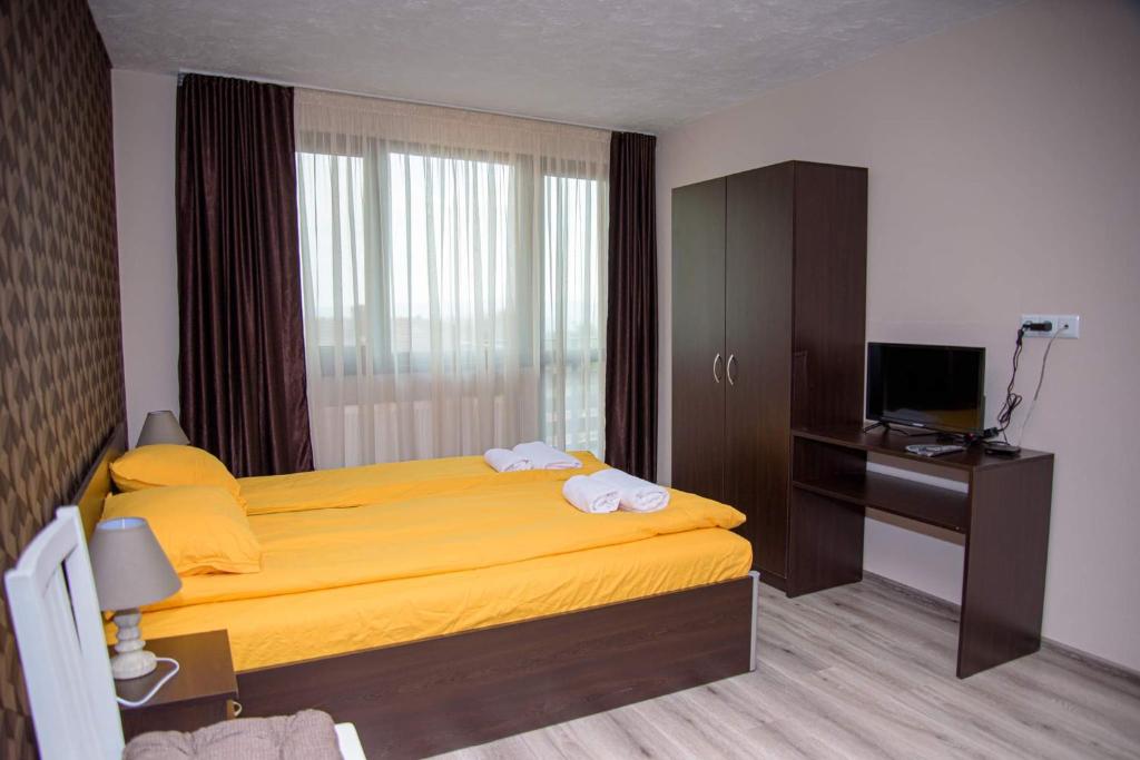 een slaapkamer met een geel bed en een televisie bij Вила Здравец in Shipka