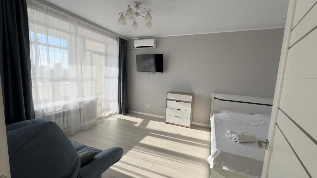 een woonkamer met een stoel en een bed bij ЖК Ауэзова1 in Köksetaw