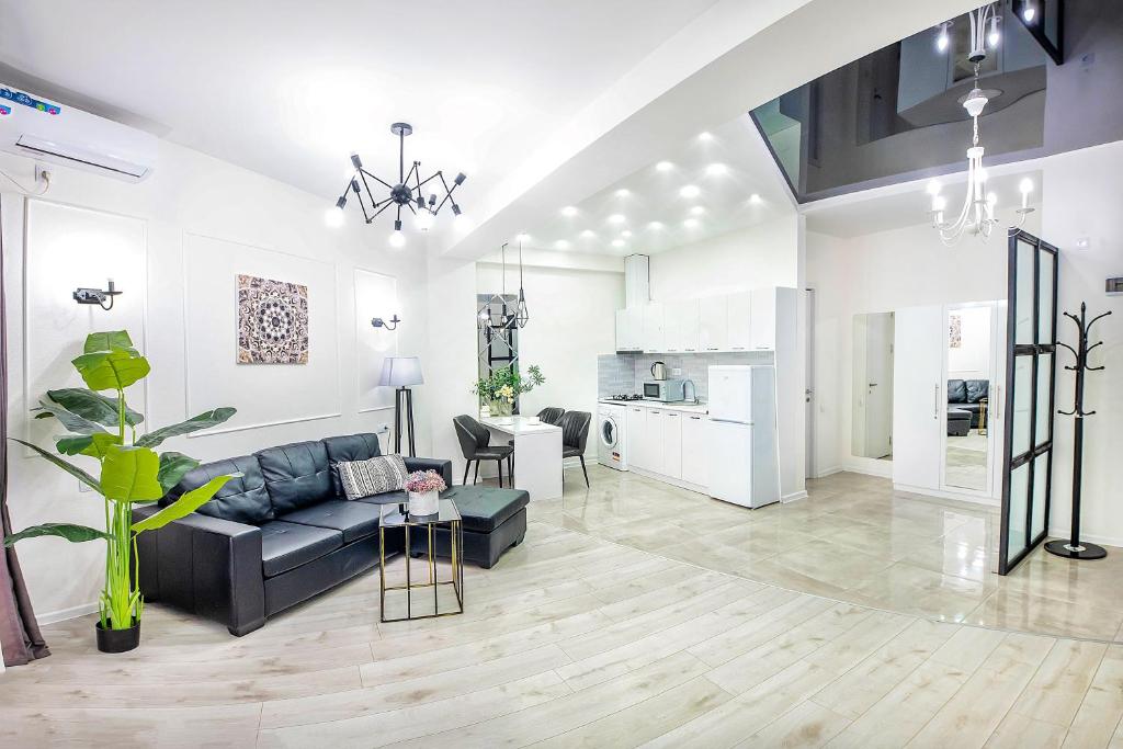 a living room with a black couch and a kitchen at HB apartments Mitskevichi in Tbilisi City