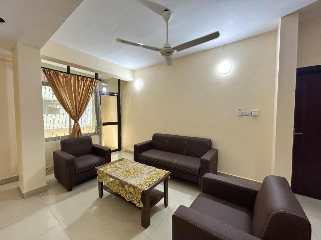 uma sala de espera com sofás, uma mesa e uma ventoinha de tecto em Karibu house em Dar es Salaam