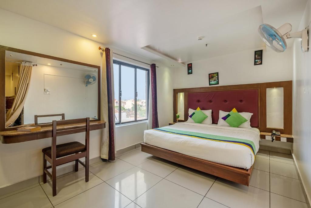a bedroom with a bed and a desk and a mirror at Treebo Trend South Avenue 700 Mts From Promenade Beach in Puducherry