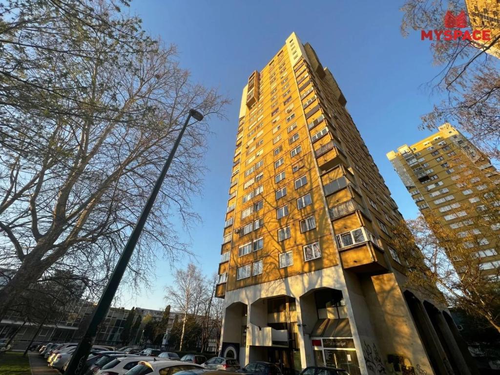 a tall yellow building next to a parking lot at Urban Charm Apartment in Sarajevo