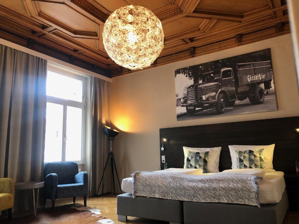 a bedroom with a large bed and a chandelier at Hotel Brauhof Wien in Vienna