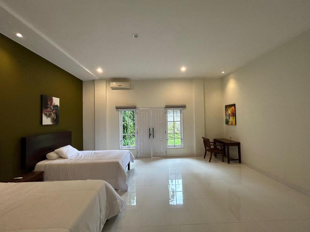1 Schlafzimmer mit 2 Betten, einem Tisch und einem Fenster in der Unterkunft Sanur House in Denpasar
