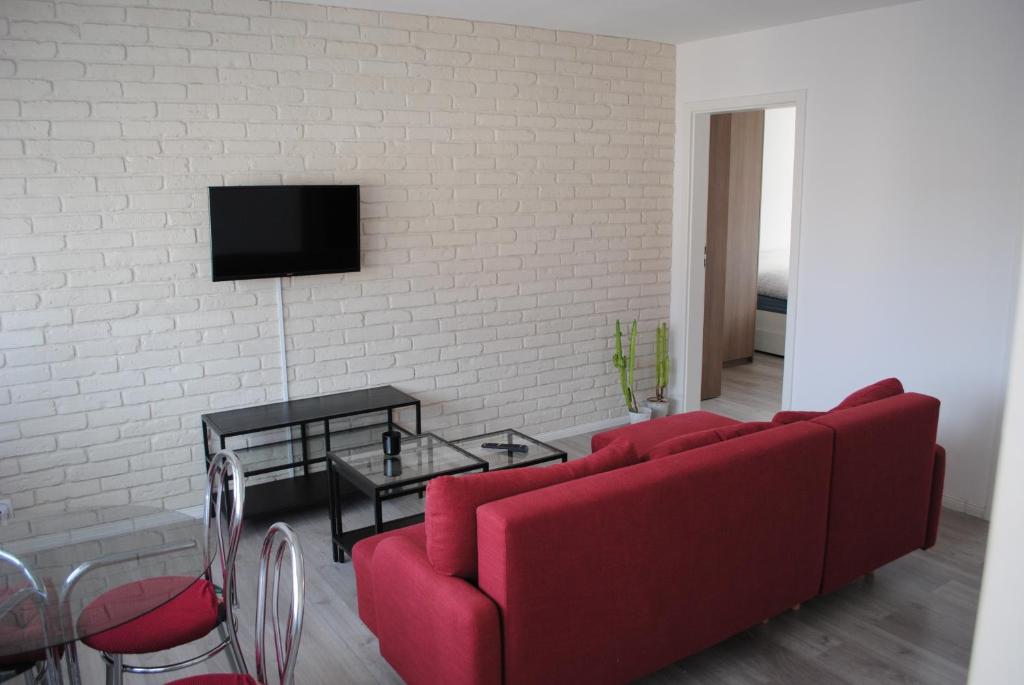 sala de estar con sofá rojo y pared de ladrillo blanco en Apartament Bukovska en Poznan