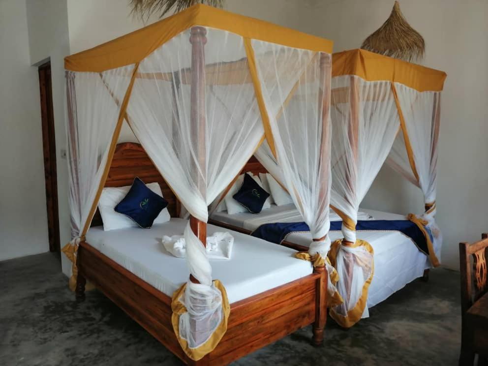 a bedroom with two beds with mosquito nets at Zangreen Bungalows in Jambiani