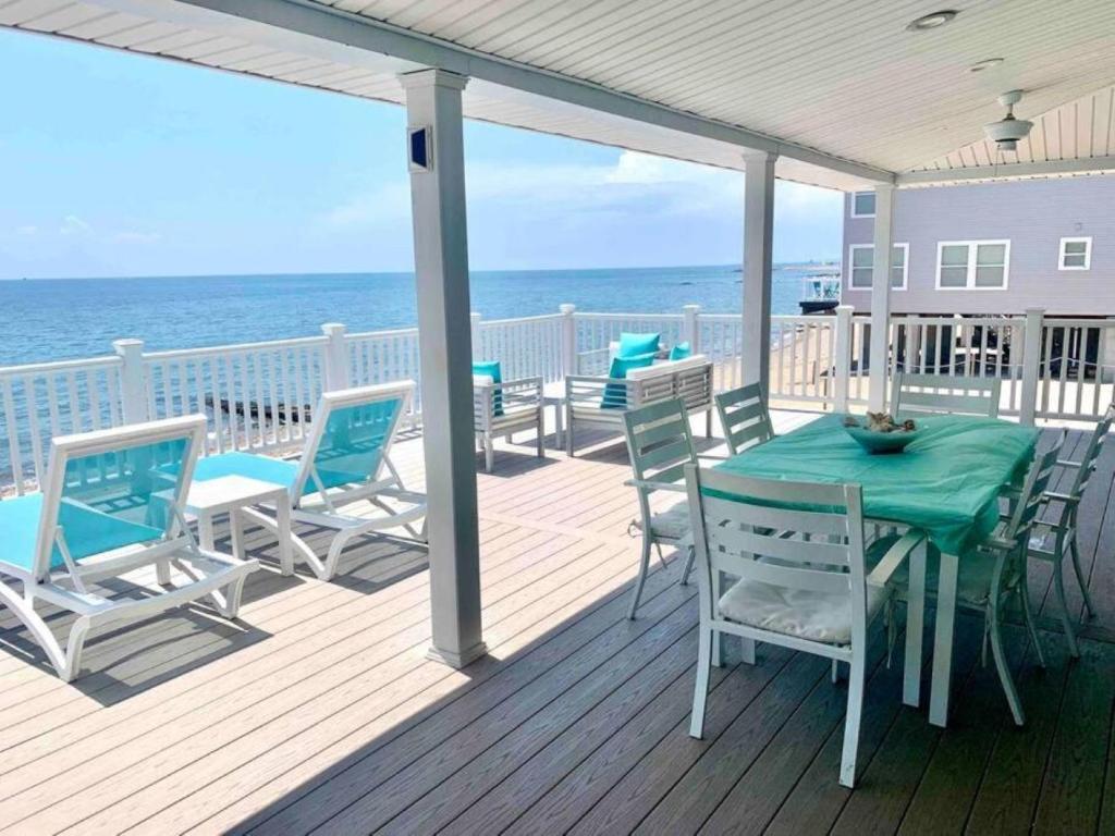 a deck with a table and chairs and the ocean at Cozy Beach - Direct Waterfront! in East Haven