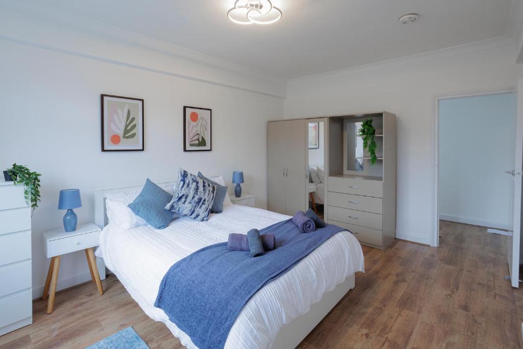 biała sypialnia z dużym łóżkiem z niebieskimi poduszkami w obiekcie Lovely 2-bed Highbury Home w Londynie