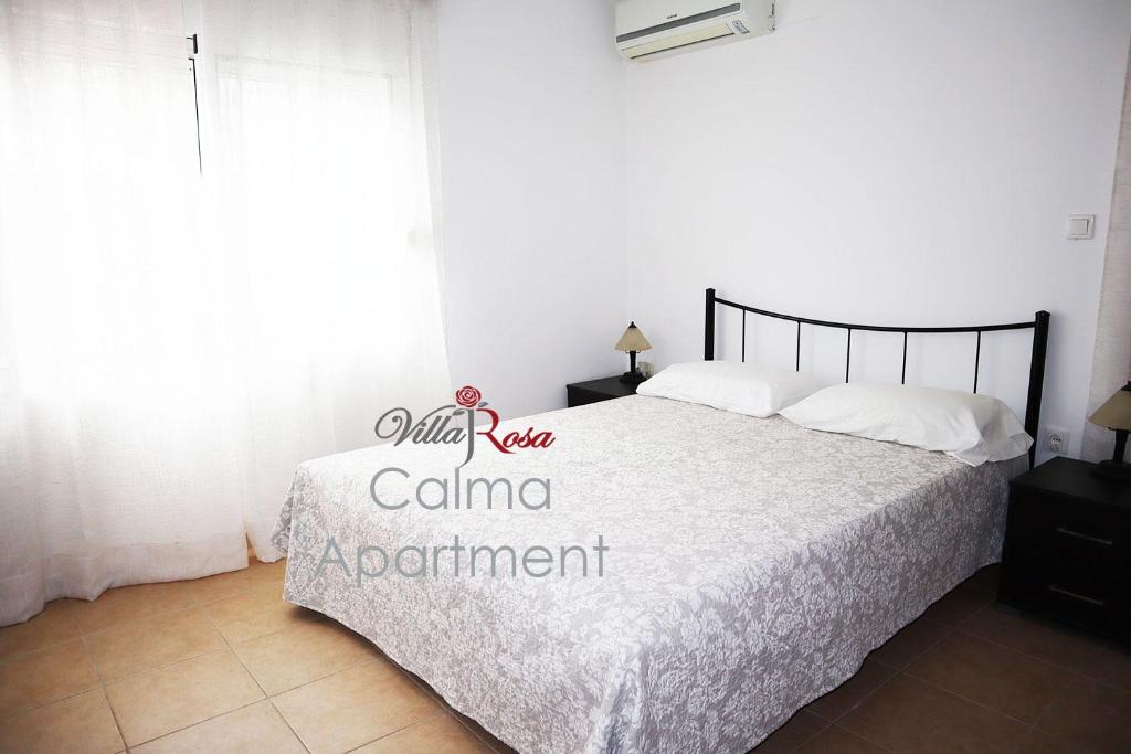 a bedroom with a bed with white sheets and a window at Villarosa Calma apartment in Stavros