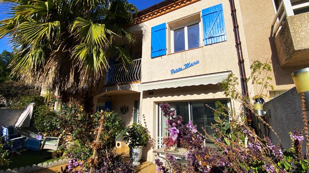 un bâtiment avec un palmier et des fleurs devant lui dans l'établissement Studio clair, climatisé avec jardin et parking, à Perpignan