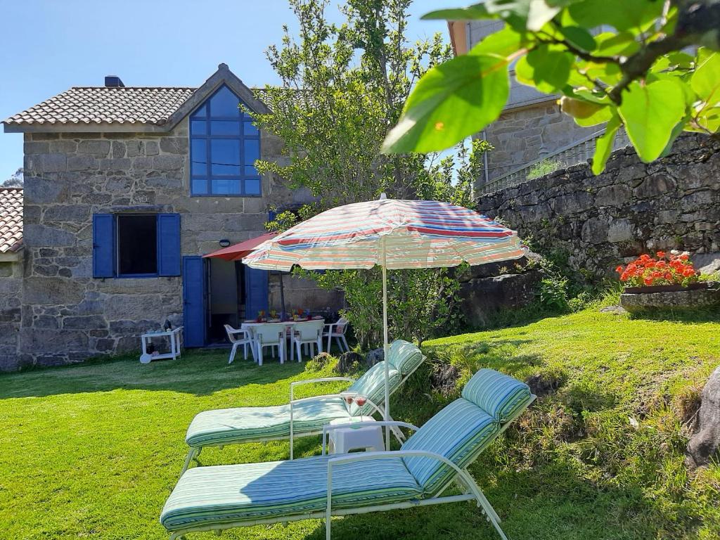 two chairs and an umbrella in a yard at Casa Campo de Cortes in Muros