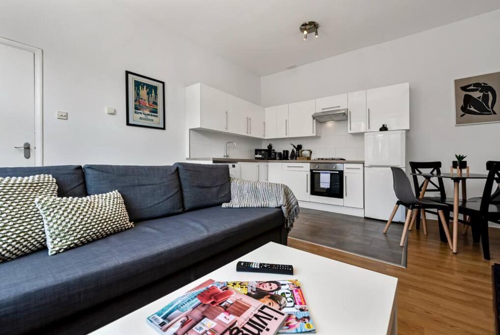 Spacious 1 bed flat close to Crouch End في لندن: غرفة معيشة مع أريكة زرقاء ومطبخ