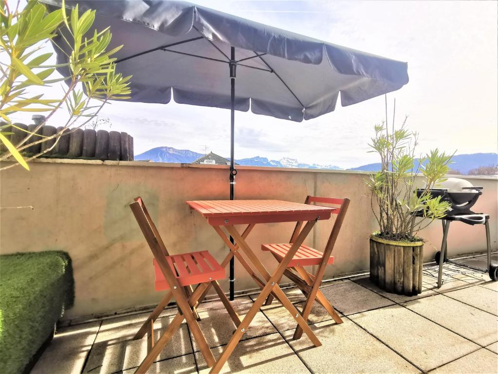 - une table, 2 chaises et un parasol sur la terrasse dans l'établissement L'Harmony 3*, 2 Vélos, Vue Montagnes, Terrasse, à Annecy