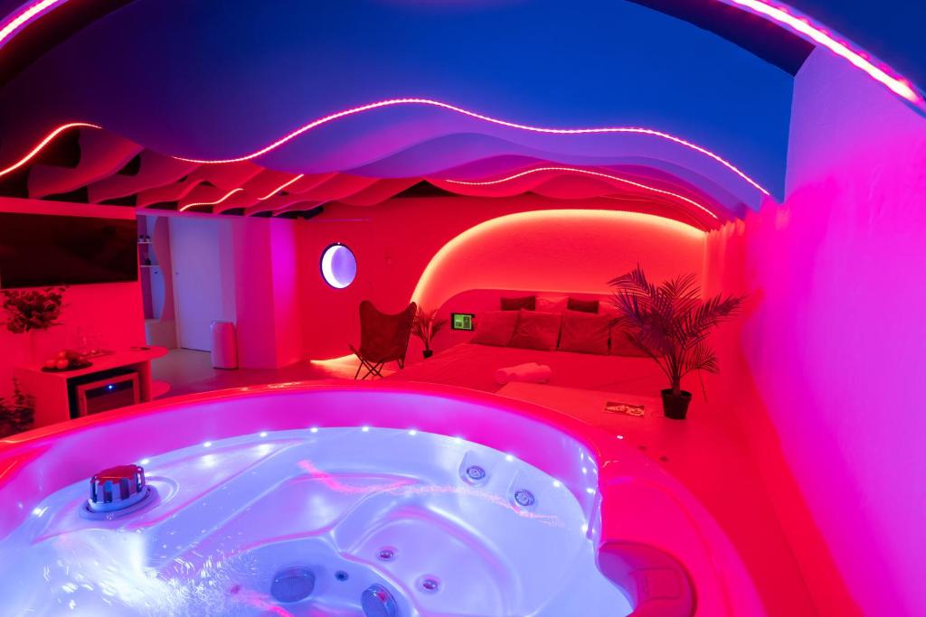 a bedroom with a bed and a tub in a room with pink lights at SPA SPA Legerova in Prague