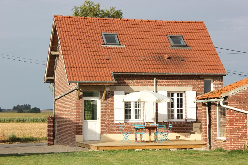 une maison en briques avec une table et un parasol dans l'établissement Gite Le petit roseau, à Canny-sur-Matz