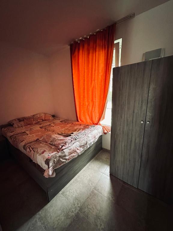 1 dormitorio con 1 cama con cortina naranja en Stella Udacha Apartments & Studios, en Sunny Beach