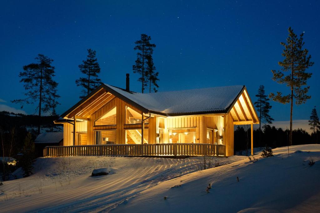 une maison en bois dans la neige la nuit dans l'établissement Stijlvolle vakantiewoning met uitzicht op het Vråvatn meer, à Vradal