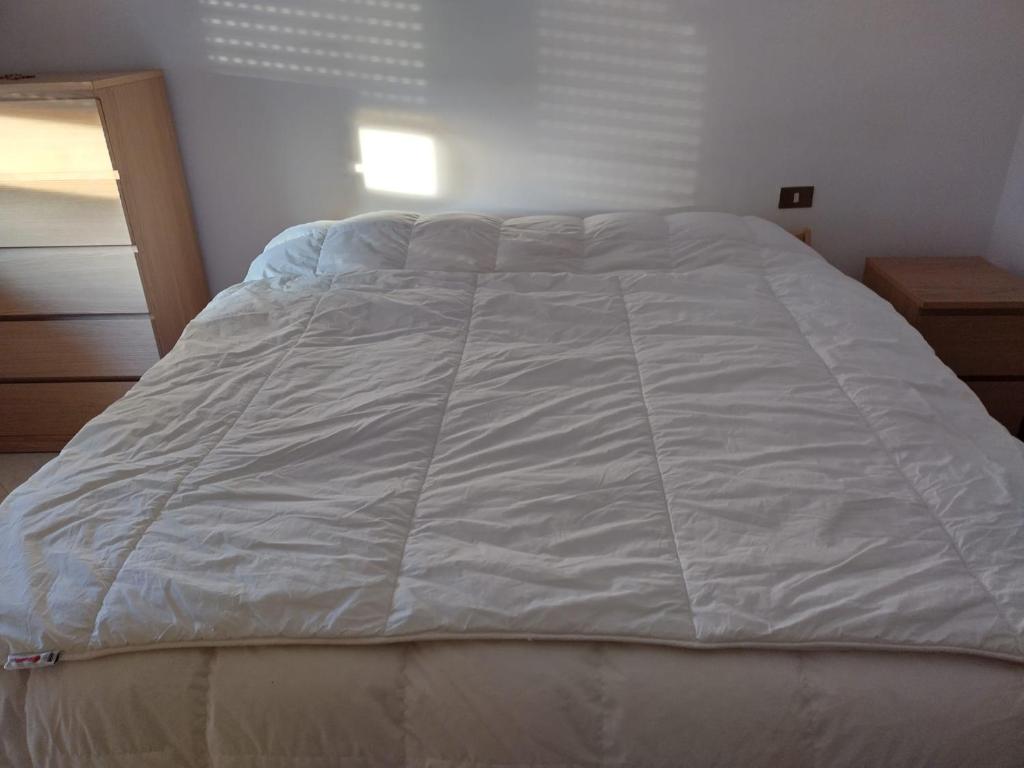 a bed with a white comforter in a bedroom at Madonna della Libera's House in Avezzano