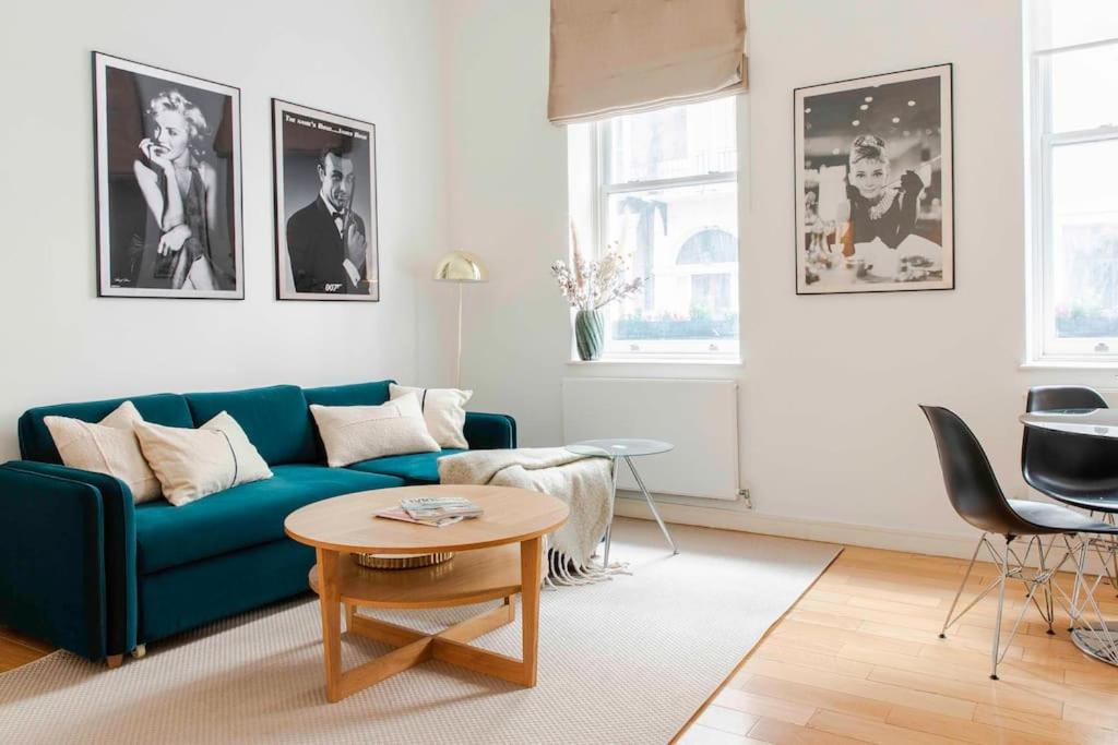 a living room with a blue couch and a table at Cosy 1 Bed Apartment in the heart of Mayfair! in London