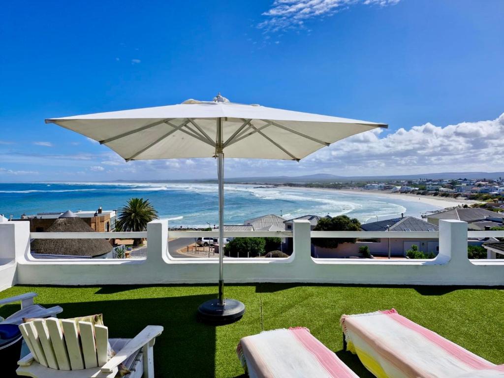 a patio with an umbrella and chairs and the beach at 16 Mile View in Yzerfontein