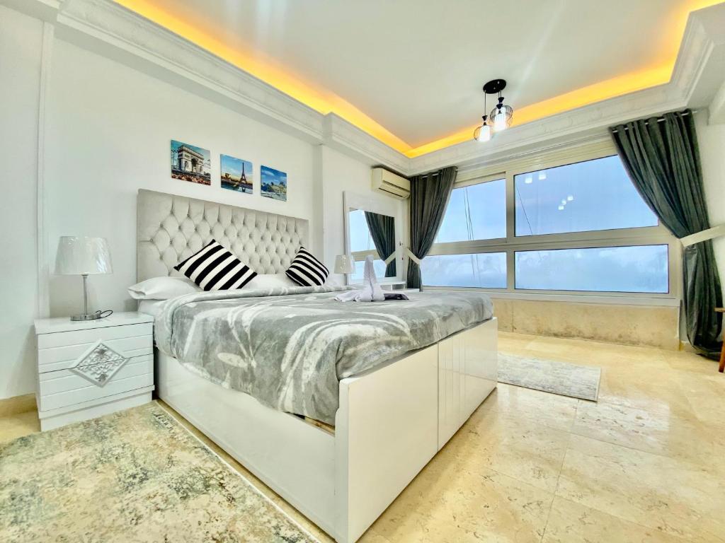 a white bedroom with a large bed and a window at Alexandria Luxury Apartments Stanley Direct Sea View in Alexandria