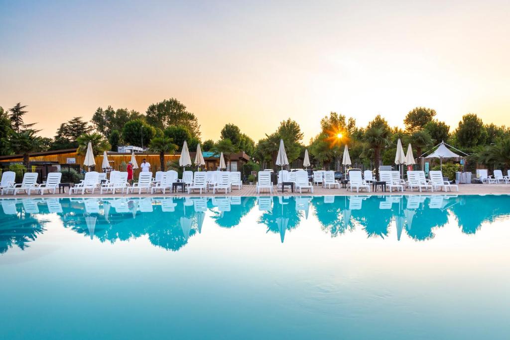 una piscina d'acqua con sedie e un resort di hu Venezia Camping in Town a Marghera