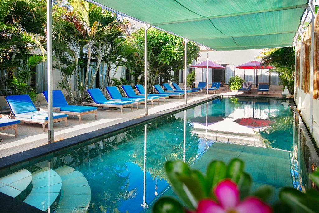 a swimming pool with blue chairs and umbrellas at Kura Kura Resort Gili Meno in Gili Meno