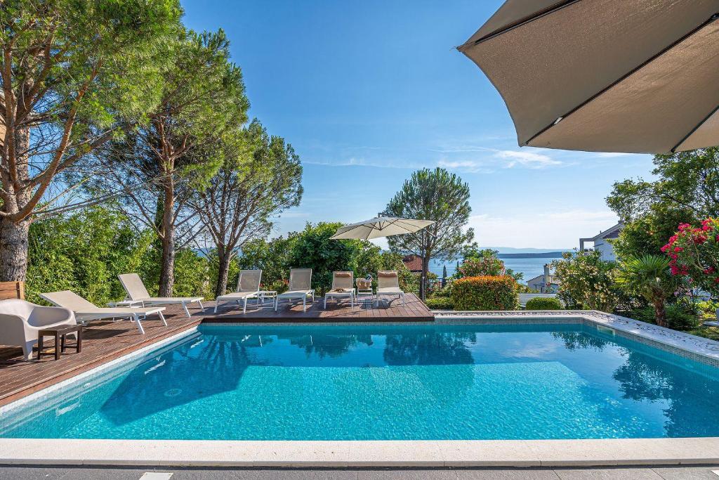 una piscina con sillas y sombrilla en Villa mit Privatpool, Whirlpool, 350 Meter zum Strand, en Dramalj
