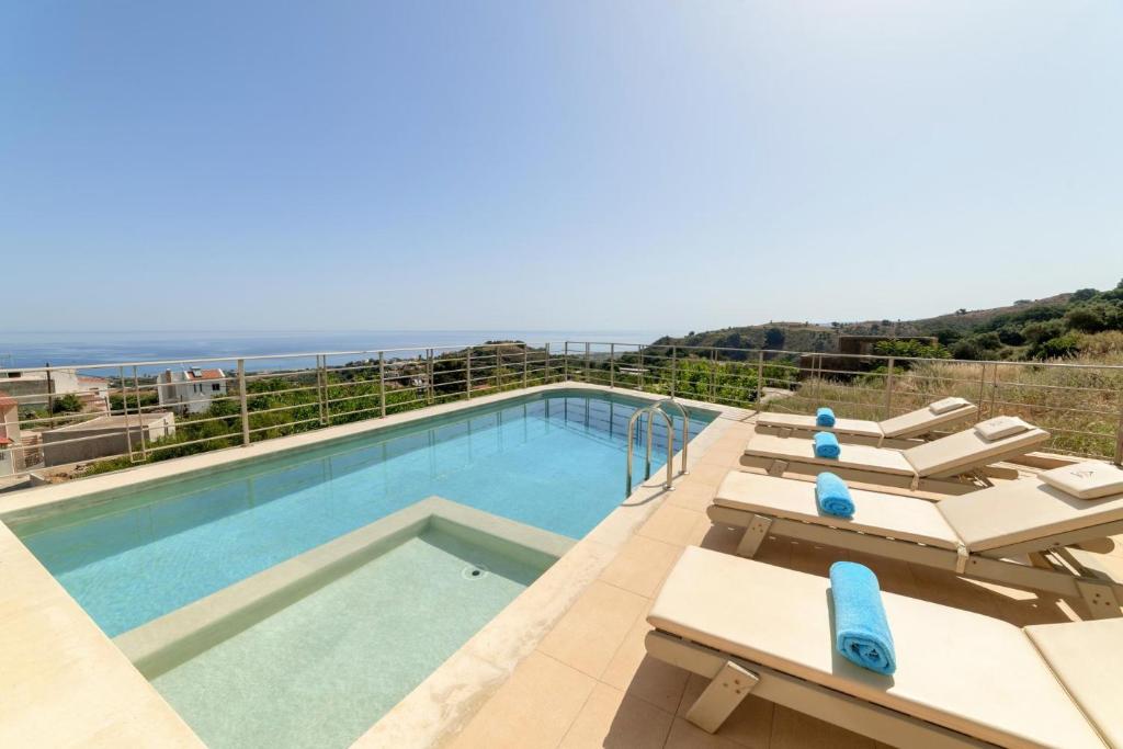 a swimming pool with lounge chairs and the ocean at Le Stelle Villa in Georgioupolis