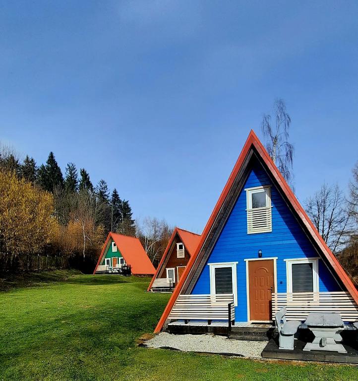 a blue house with two benches in a field at Kolorowe Wzgórze Zagórze in Zagórze Śląskie