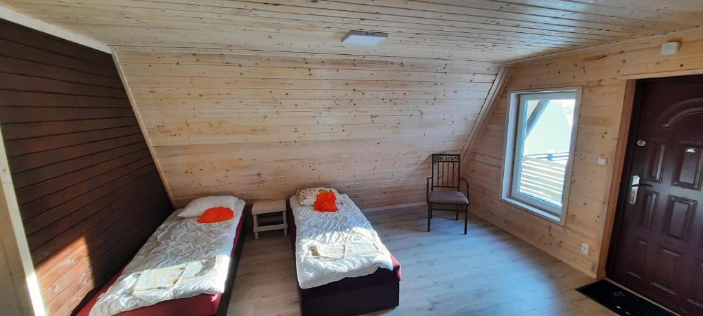 - une chambre avec 2 lits dans une cabane en rondins dans l'établissement Kolorowe Wzgórze Zagórze, à Zagórze Śląskie