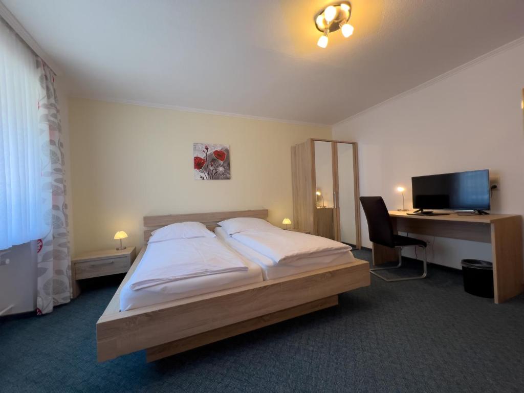 a bedroom with a bed and a desk with a computer at Hotel Haus Christel in Willingen