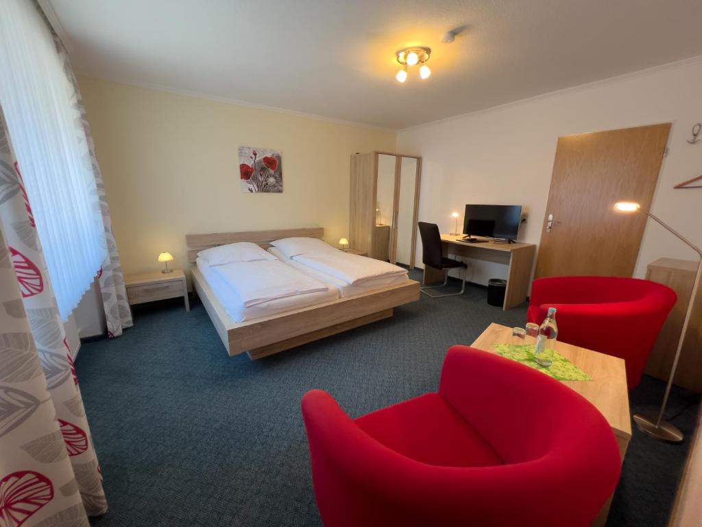 a hotel room with a bed and red chairs at Hotel Haus Christel in Willingen