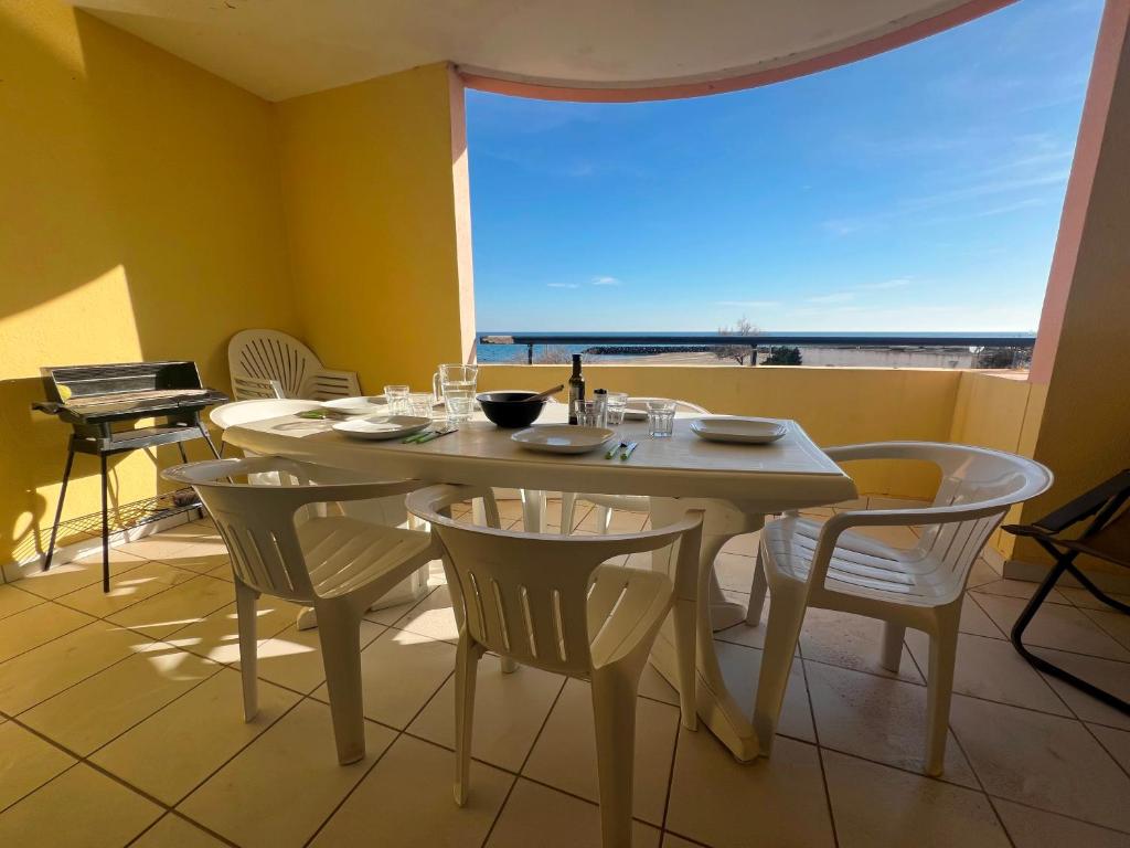 une salle à manger avec une table et des chaises et une grande fenêtre dans l'établissement SAVANNA BEACH I Joli 2 pièces cabine vue mer piscine Rochelongue Cap d'Agde, au Cap d'Agde