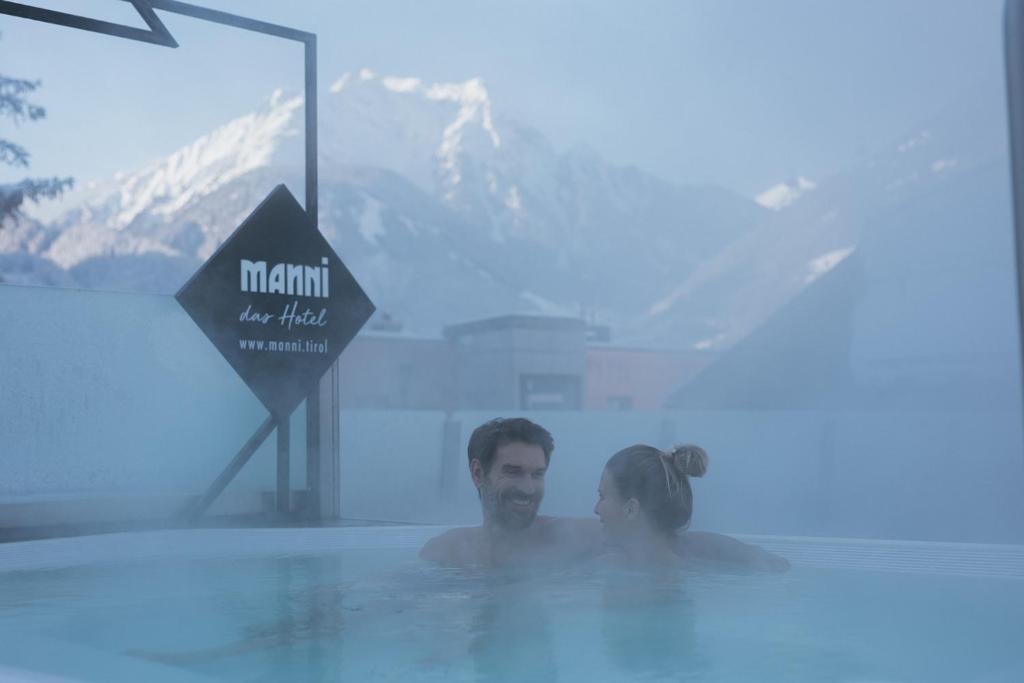 Ein Mann und eine Frau sitzen im Pool in der Unterkunft MANNI das Hotel in Mayrhofen