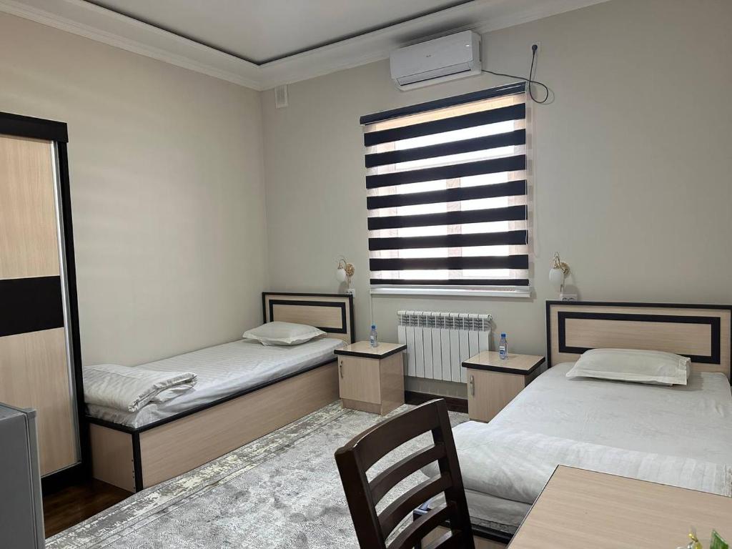 a bedroom with two beds and a window and a table at HOTEL ARAL in Nukus
