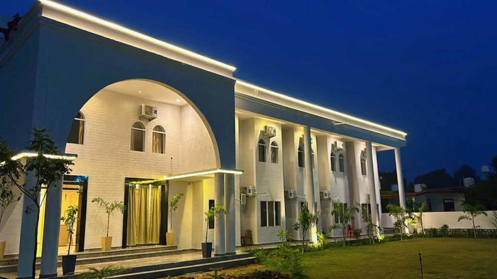 a large white building with an archway at night at Farm Green View Resort in Orchha