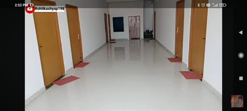 an empty hallway with doors and a white floor at Premshi Guest House in Ayodhya