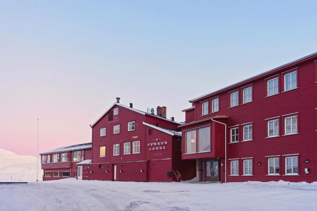 a red building with snow in front of it at Funken Lodge in Longyearbyen