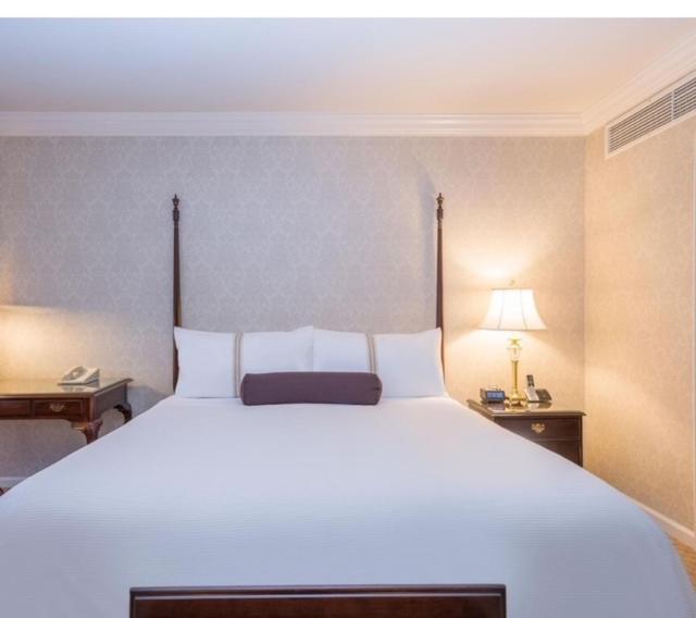 una camera da letto con un grande letto bianco con due tavoli e una lampada di LA PLANETTE LODGE & BAR a Gisenyi