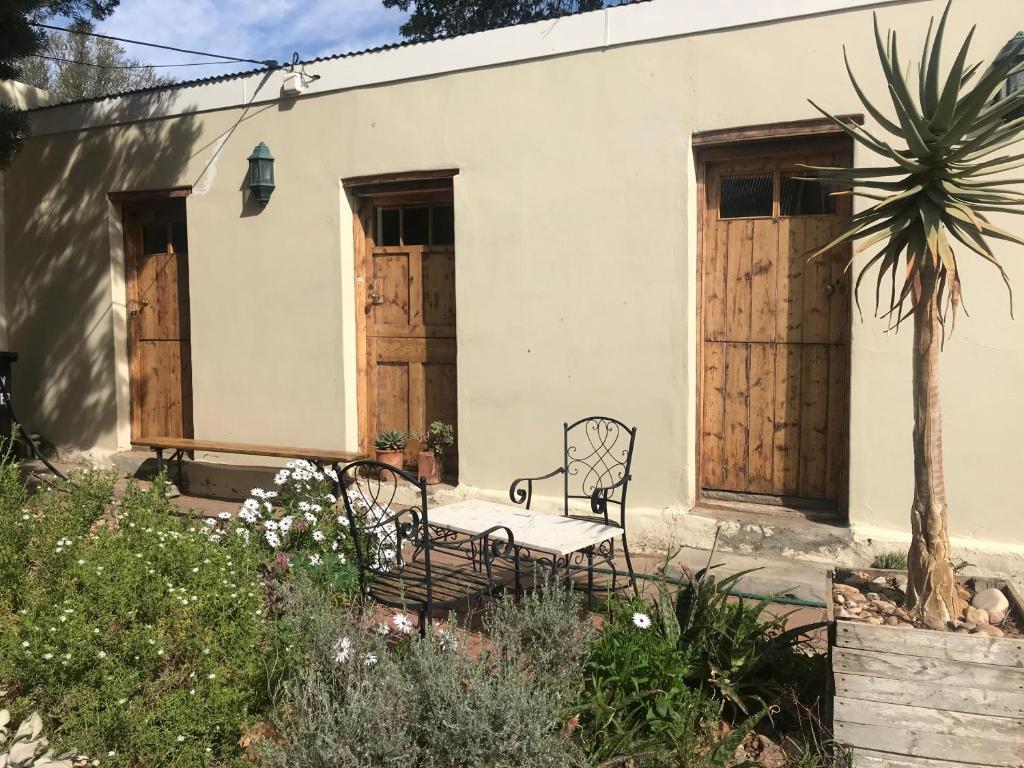 a house with wooden doors and a bench in a garden at ArtKaroo Stay in Oudtshoorn